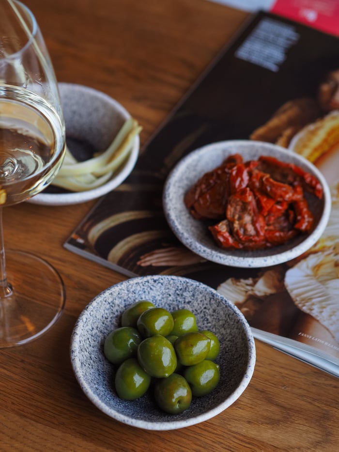 The Art of Drawing Readers In: Your attractive post title goes here A gourmet spread featuring olives, dried tomatoes, and wine on a wooden table.