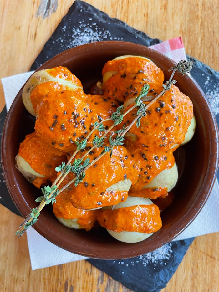 Traditional Canarian papas arrugadas topped with spicy red mojo sauce, a savory delight.