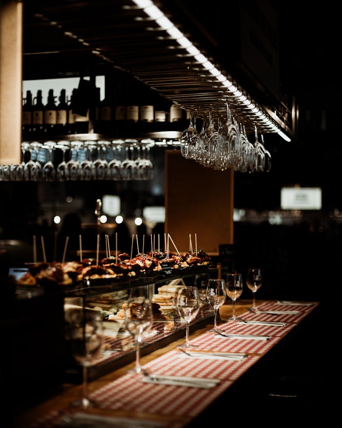 Dimly lit restaurant showcasing tapas and wine glasses on a wooden bar.